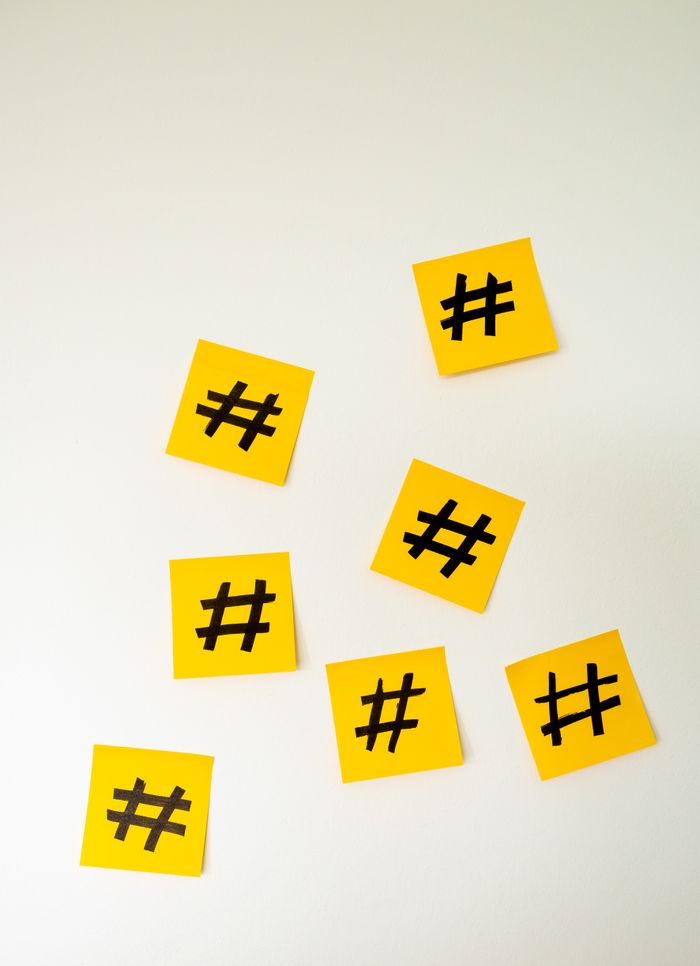 Close-up of yellow sticky notes with hashtag symbols arranged on a white background.